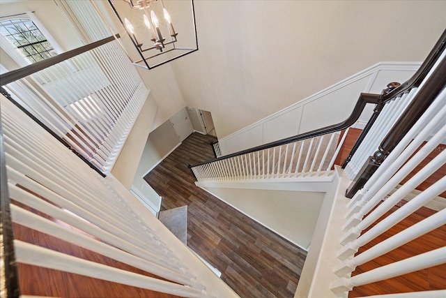 staircase with wood finished floors and an inviting chandelier