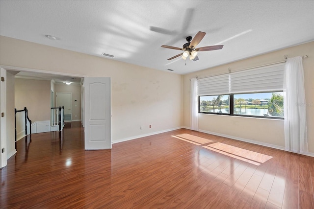 spare room featuring a textured ceiling, ceiling fan, wood finished floors, and baseboards