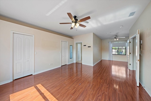 unfurnished living room with wood finished floors, visible vents, and baseboards