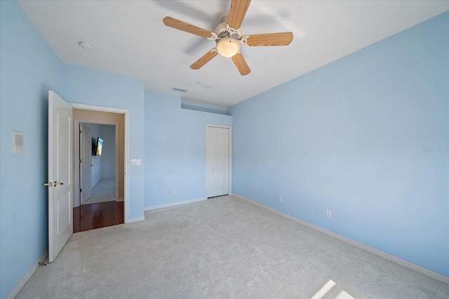 unfurnished bedroom with carpet floors, a closet, visible vents, a ceiling fan, and baseboards