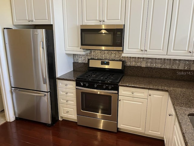 kitchen featuring stainless steel appliances, white cabinetry, dark wood-type flooring, and dark stone counters