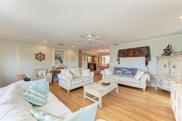 living area featuring crown molding, light wood-style floors, ceiling fan with notable chandelier, and recessed lighting
