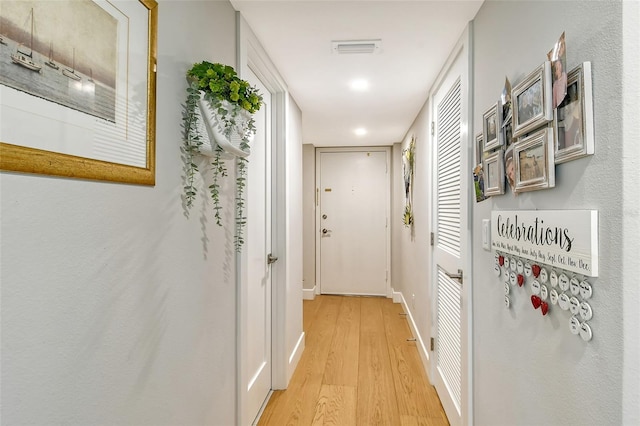 hallway with visible vents, baseboards, and light wood-style flooring