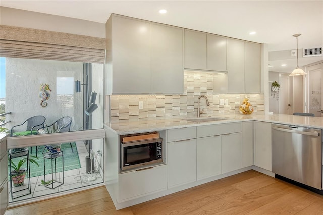 kitchen featuring visible vents, decorative backsplash, appliances with stainless steel finishes, light wood-style floors, and a sink