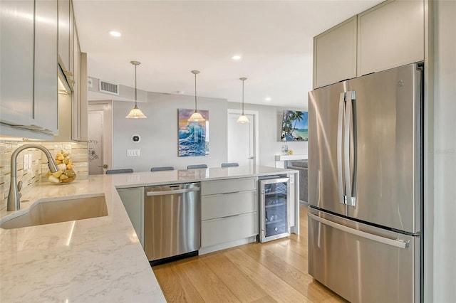 kitchen featuring beverage cooler, visible vents, a sink, appliances with stainless steel finishes, and backsplash