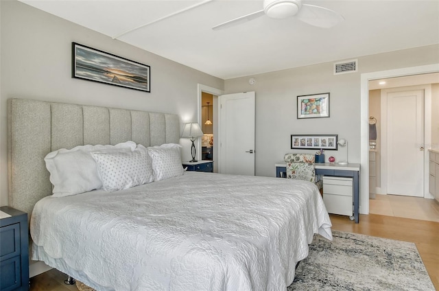 bedroom with ceiling fan, visible vents, and wood finished floors