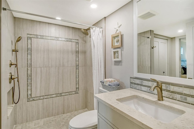 full bathroom with a tile shower, visible vents, toilet, and vanity