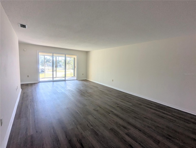 empty room with dark wood finished floors, visible vents, baseboards, and a textured ceiling