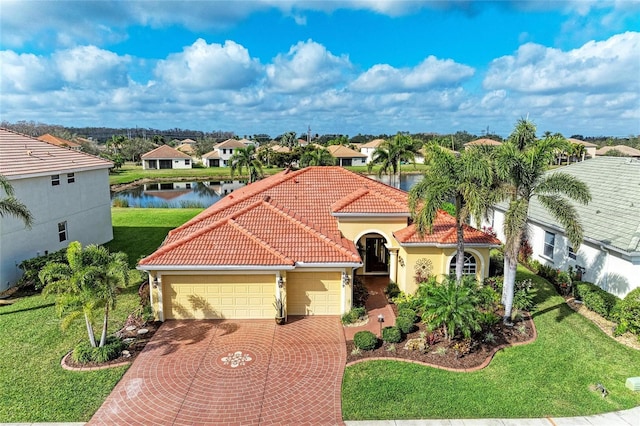 mediterranean / spanish-style home featuring a water view, a garage, and a front lawn