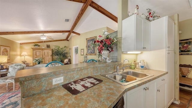 kitchen featuring visible vents, open floor plan, a peninsula, white cabinetry, and a sink