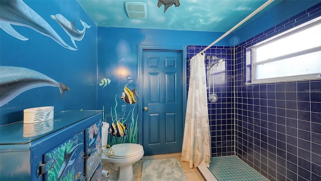 bathroom with a tile shower, toilet, and tile patterned floors