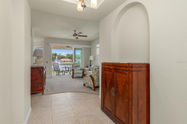 hall featuring baseboards, light tile patterned floors, and light colored carpet