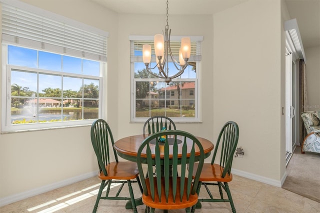 dining area with a water view, baseboards, and a chandelier