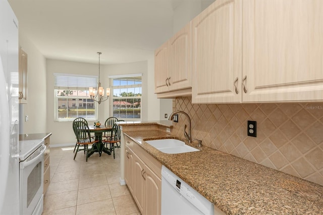 kitchen with white appliances, tasteful backsplash, decorative light fixtures, light stone countertops, and a sink