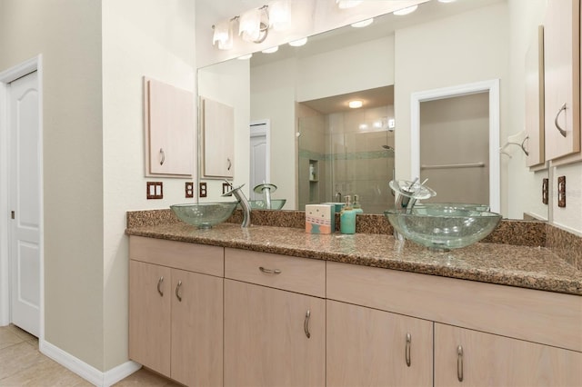 full bath featuring double vanity, a stall shower, baseboards, and a sink