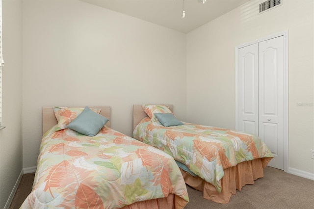 carpeted bedroom featuring a closet, visible vents, and baseboards