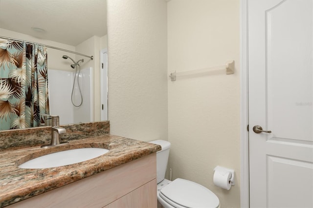 full bathroom featuring toilet, a shower with curtain, a textured wall, and vanity