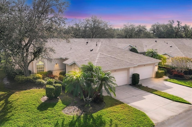 view of front of home with an attached garage, stucco siding, concrete driveway, and a yard