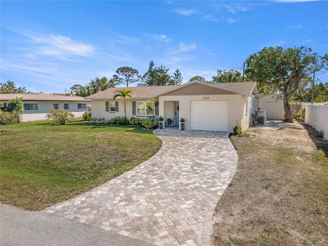 ranch-style house featuring a front yard, decorative driveway, fence, and an attached garage