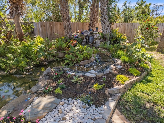 view of yard featuring a garden pond and fence