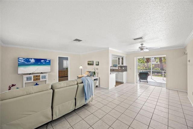 living area with light tile patterned flooring, visible vents, a textured ceiling, and ornamental molding