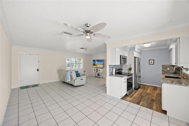 kitchen with white cabinetry, stainless steel appliances, and open floor plan