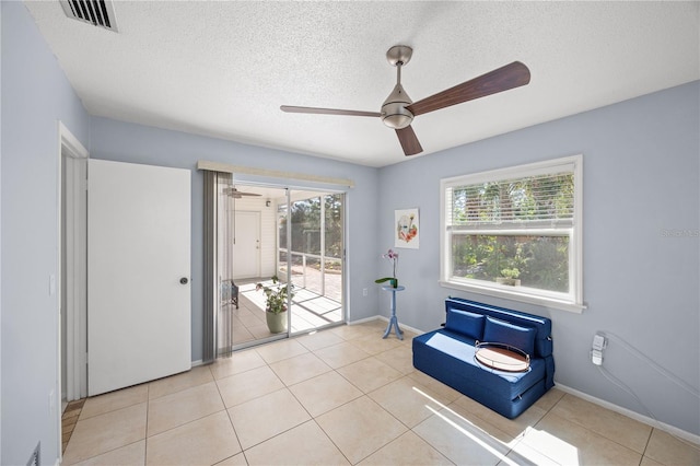 living area with visible vents, a textured ceiling, baseboards, and light tile patterned floors