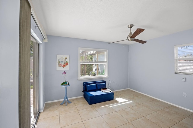 living area with a healthy amount of sunlight, ceiling fan, a textured ceiling, and light tile patterned floors