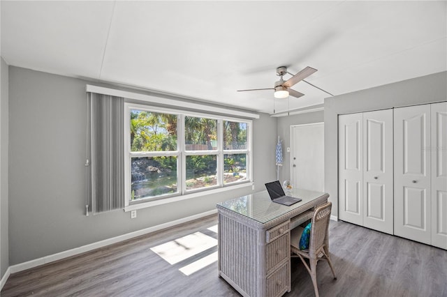 home office with a ceiling fan, light wood finished floors, and baseboards