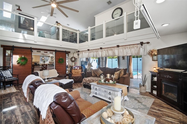 living room with dark wood-type flooring, ceiling fan, and a towering ceiling