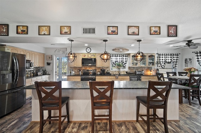 kitchen with appliances with stainless steel finishes, a kitchen bar, a kitchen island, and backsplash