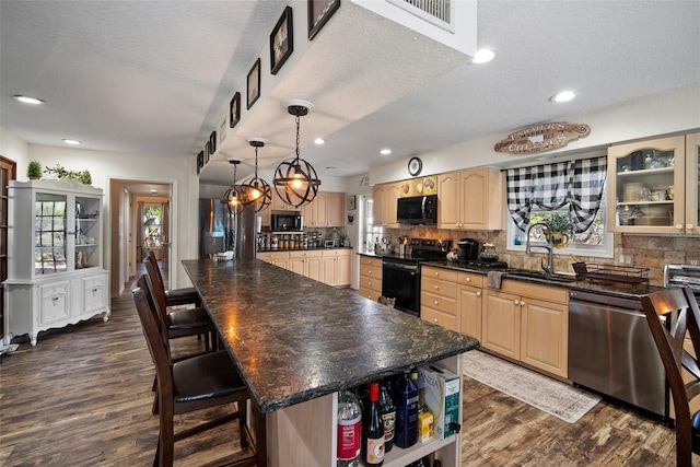 kitchen with sink, tasteful backsplash, light brown cabinets, a kitchen island, and black appliances