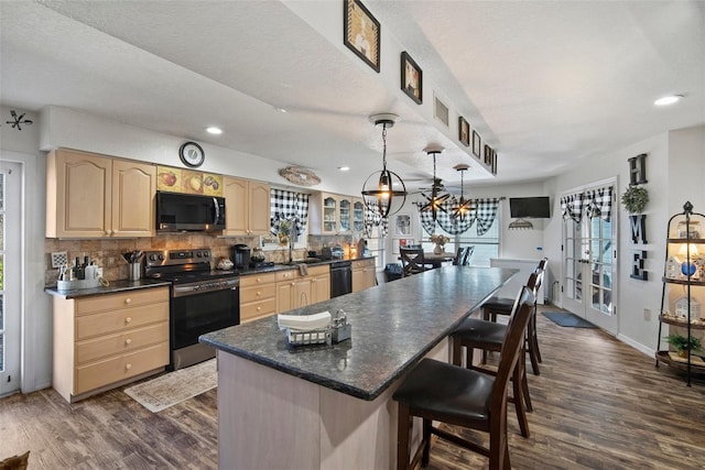 kitchen featuring decorative light fixtures, tasteful backsplash, dark hardwood / wood-style flooring, a center island, and black appliances