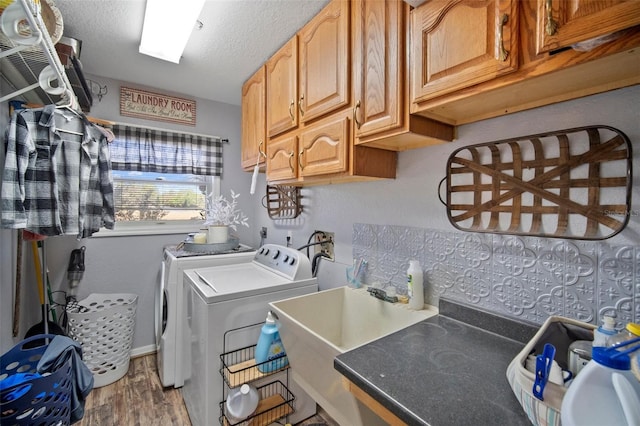 washroom featuring separate washer and dryer, sink, cabinets, hardwood / wood-style flooring, and a textured ceiling