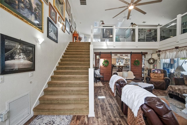 staircase with hardwood / wood-style flooring, a towering ceiling, and ceiling fan