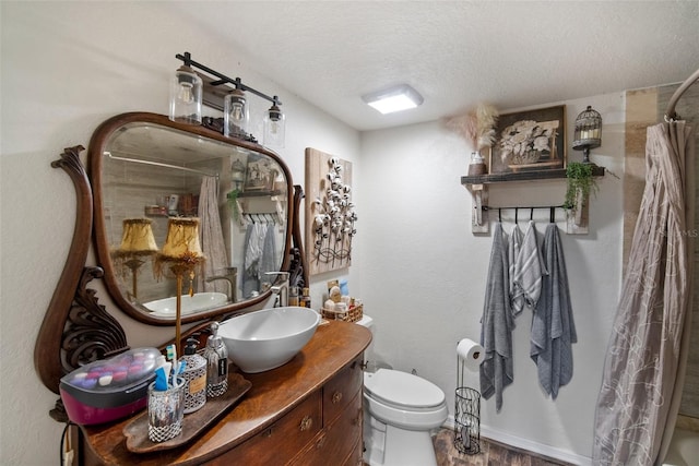 bathroom with vanity, toilet, and a textured ceiling