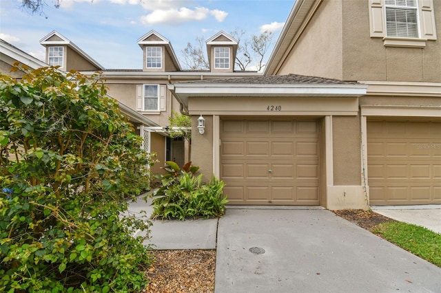 view of front facade with a garage, concrete driveway, and stucco siding