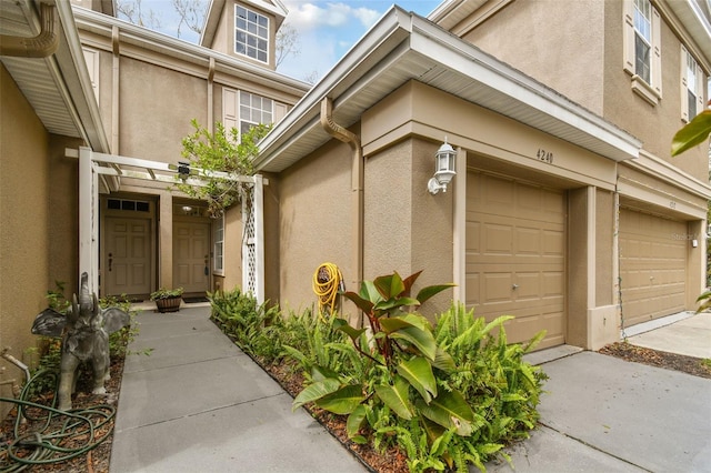 doorway to property featuring an attached garage and stucco siding