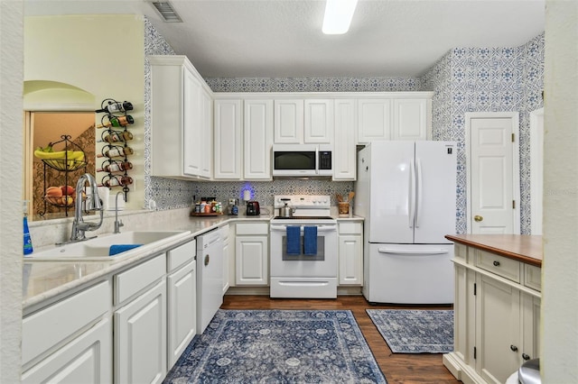 kitchen featuring light countertops, visible vents, white cabinetry, a sink, and white appliances