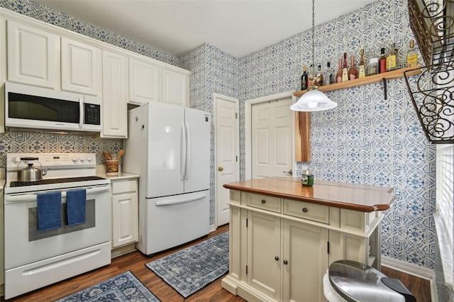 kitchen featuring white appliances, hanging light fixtures, dark wood-style flooring, and wallpapered walls