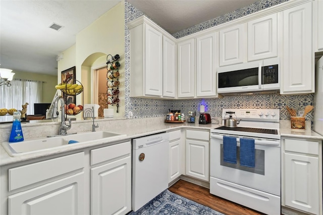 kitchen with white appliances, visible vents, white cabinetry, and light countertops