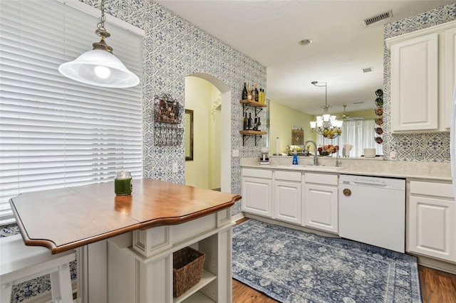 kitchen with wallpapered walls, visible vents, a peninsula, white dishwasher, and light countertops