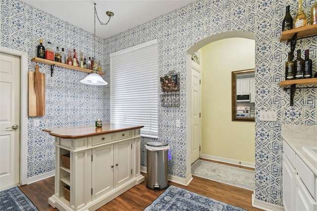 kitchen with wallpapered walls, white microwave, decorative light fixtures, light countertops, and open shelves