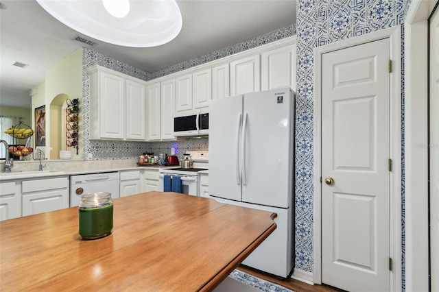 kitchen featuring light countertops, white appliances, a sink, and white cabinetry