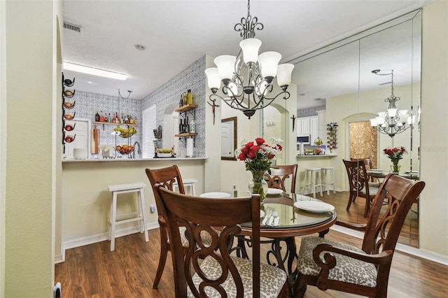 dining room with dark wood finished floors, visible vents, and a notable chandelier