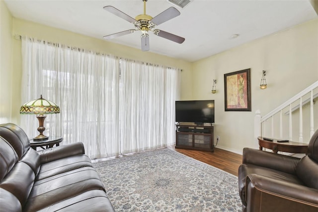 living area featuring visible vents, stairway, a ceiling fan, wood finished floors, and baseboards