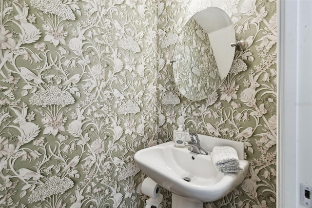 bathroom with a sink and wallpapered walls