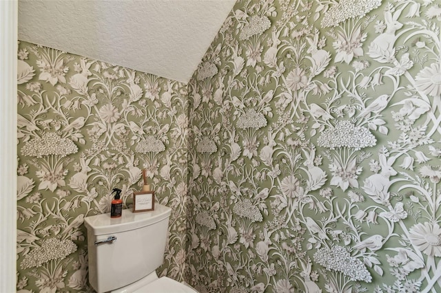 bathroom with toilet, wallpapered walls, and a textured ceiling