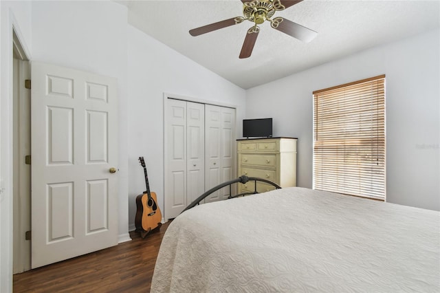 bedroom with lofted ceiling, ceiling fan, dark wood-type flooring, and a closet