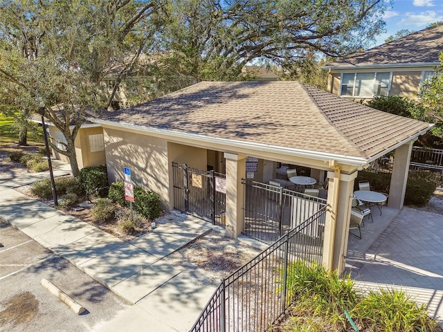 exterior space featuring roof with shingles, a gate, fence, a patio area, and stucco siding